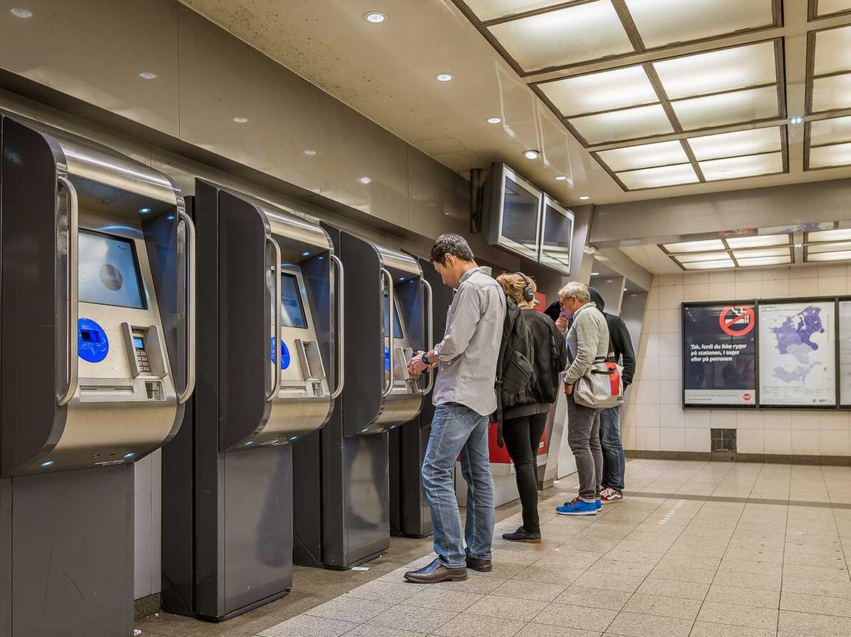 Mennesker køber billetter i billetautomater på station