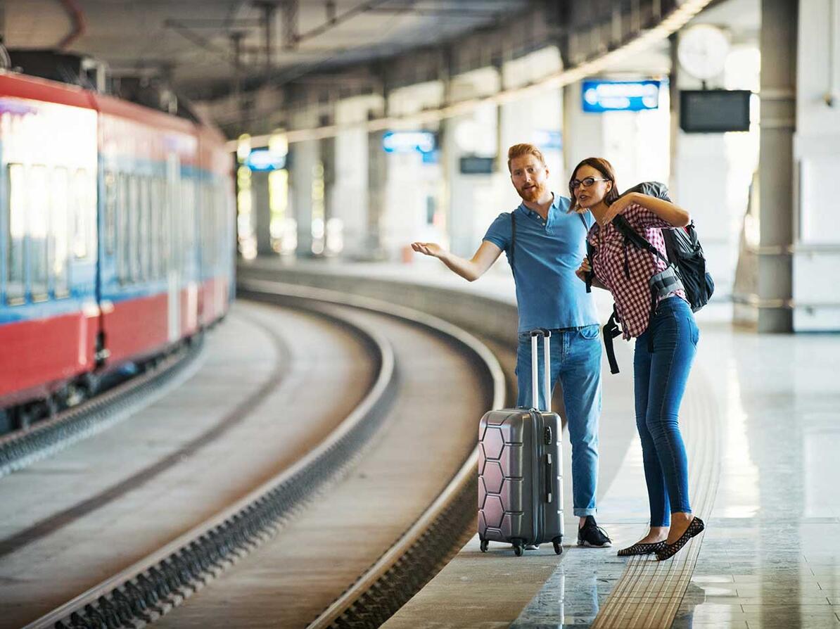 Passagerer står på togperron kigger efter toget 