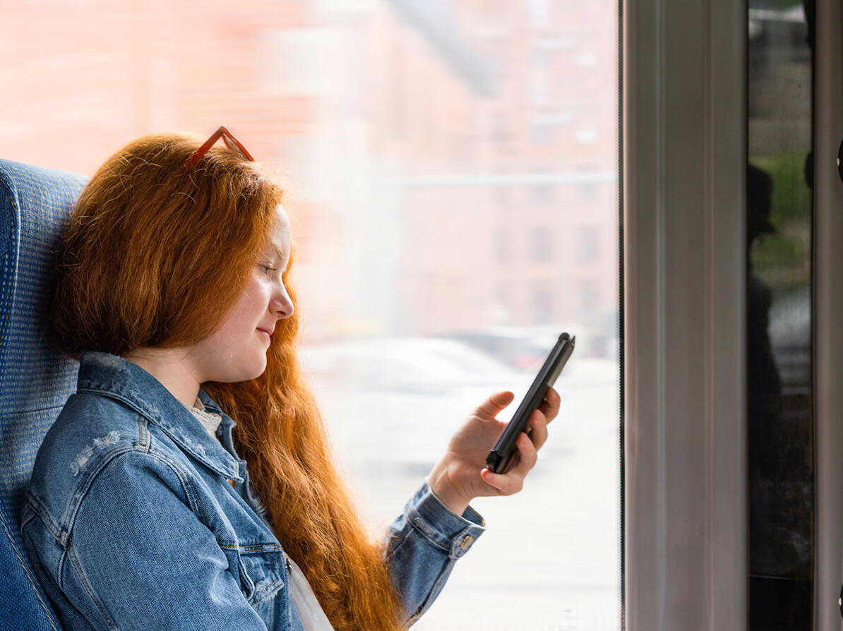 Passager sidder i bussen og kigger på sin mobiltelefon