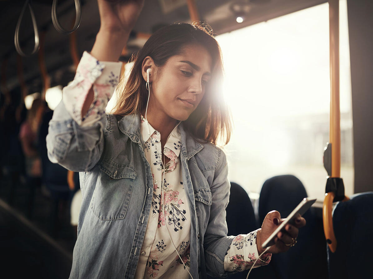 Passager står i bus og kigger på sin mobiltelefon