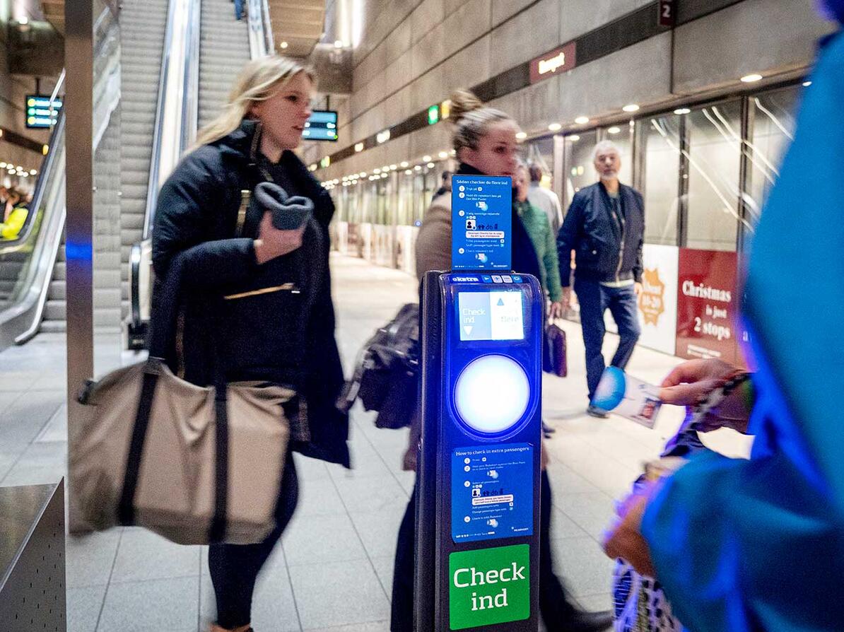 Rejsekortstander på metrostation med passagerer i baggrunden