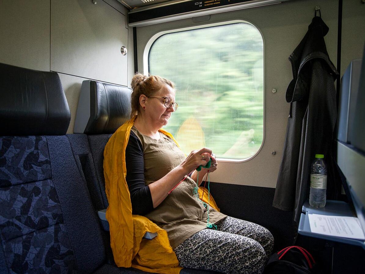 Kvinde sidder og strikker i toget