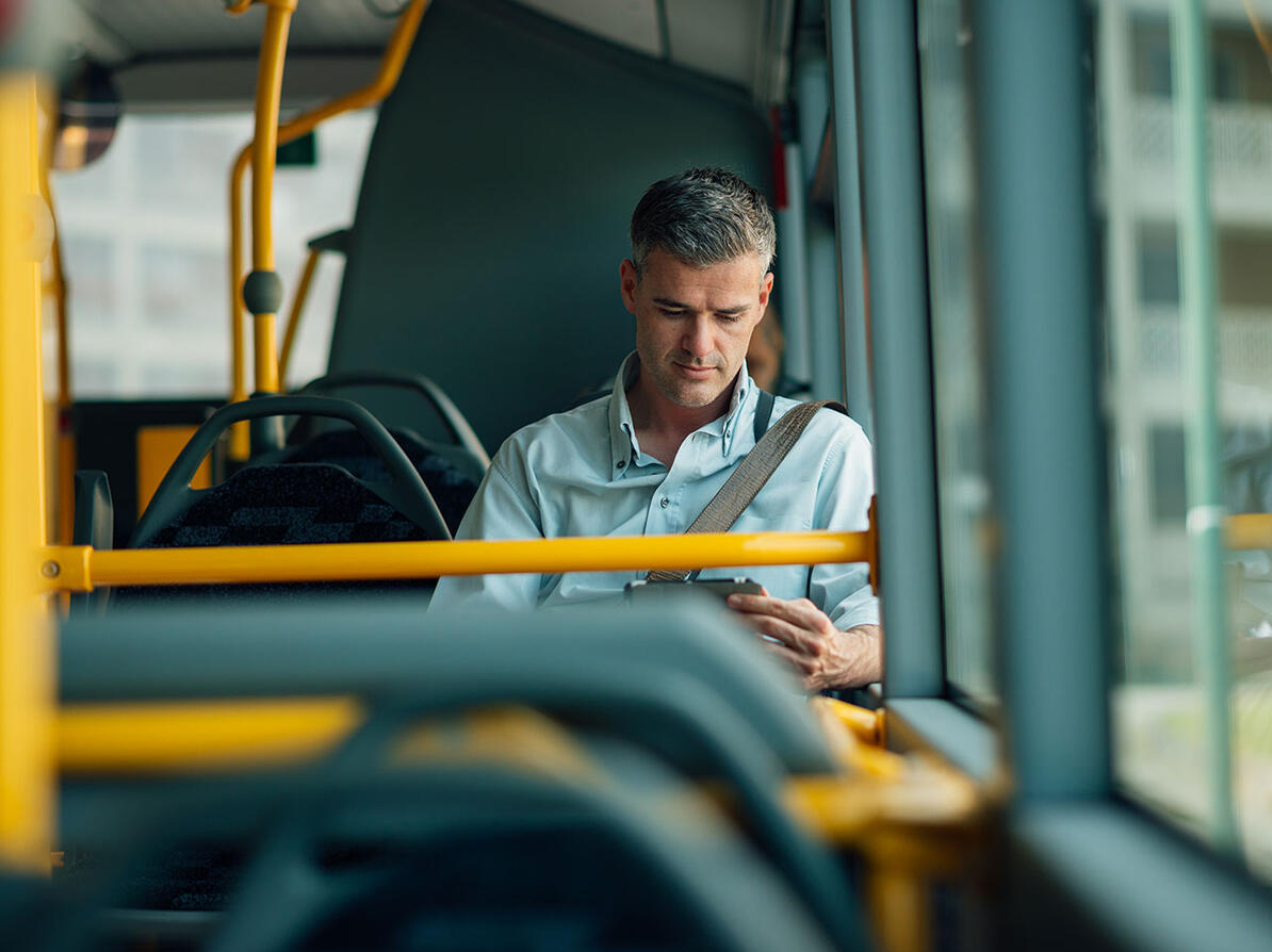 Passager sidder i bussen og kigger på sin mobiltelefon