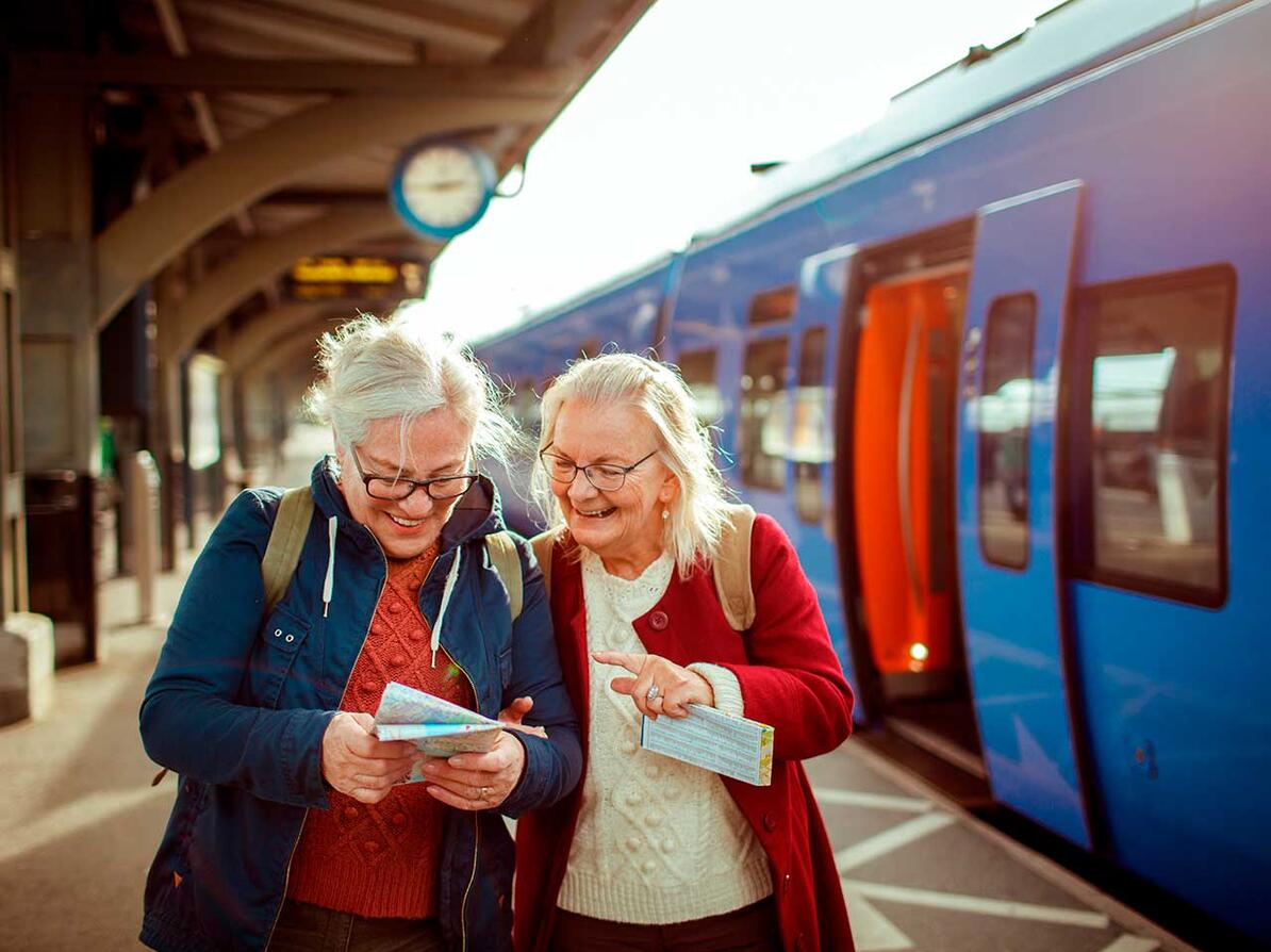 To passagerer står på perron og kigger på kort 