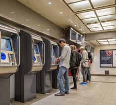 Mennesker køber billetter i billetautomater på station