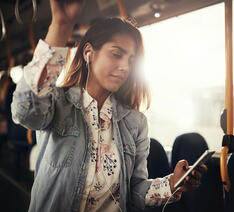 Passager står i bus og kigger på sin mobiltelefon