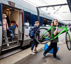Passager bærer cykel ud af tog