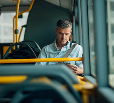 Passager sidder i bussen og kigger på sin mobiltelefon