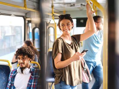 Kvinde i bus med digitalt klippekort eller mobilbillet på telefonen