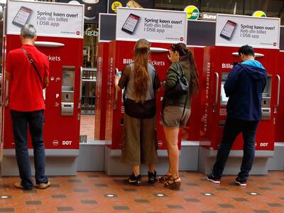 Mennesker køber billetter i billetautomater på station