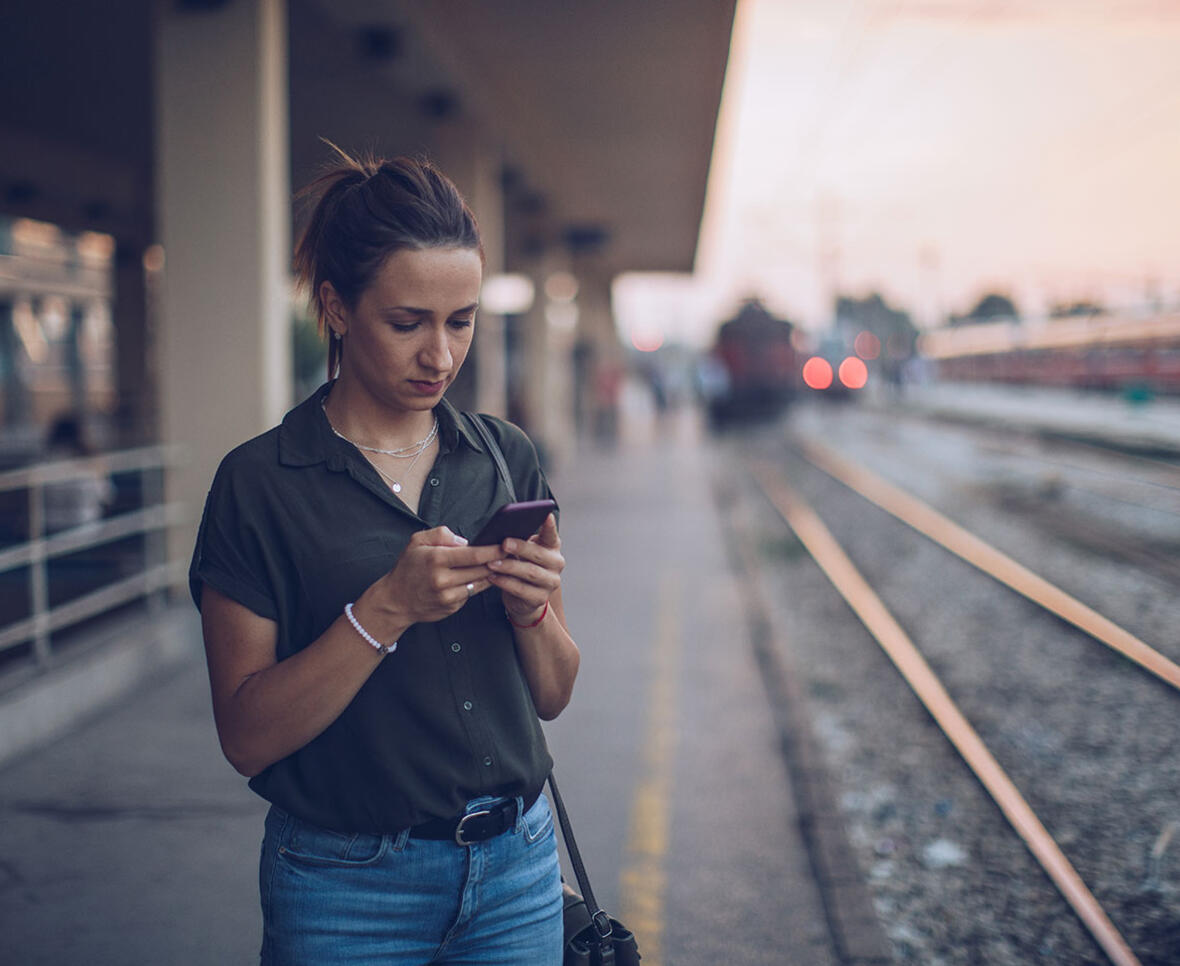 Kvinde på station ser på klagemuligheder på sin mobiltelefon